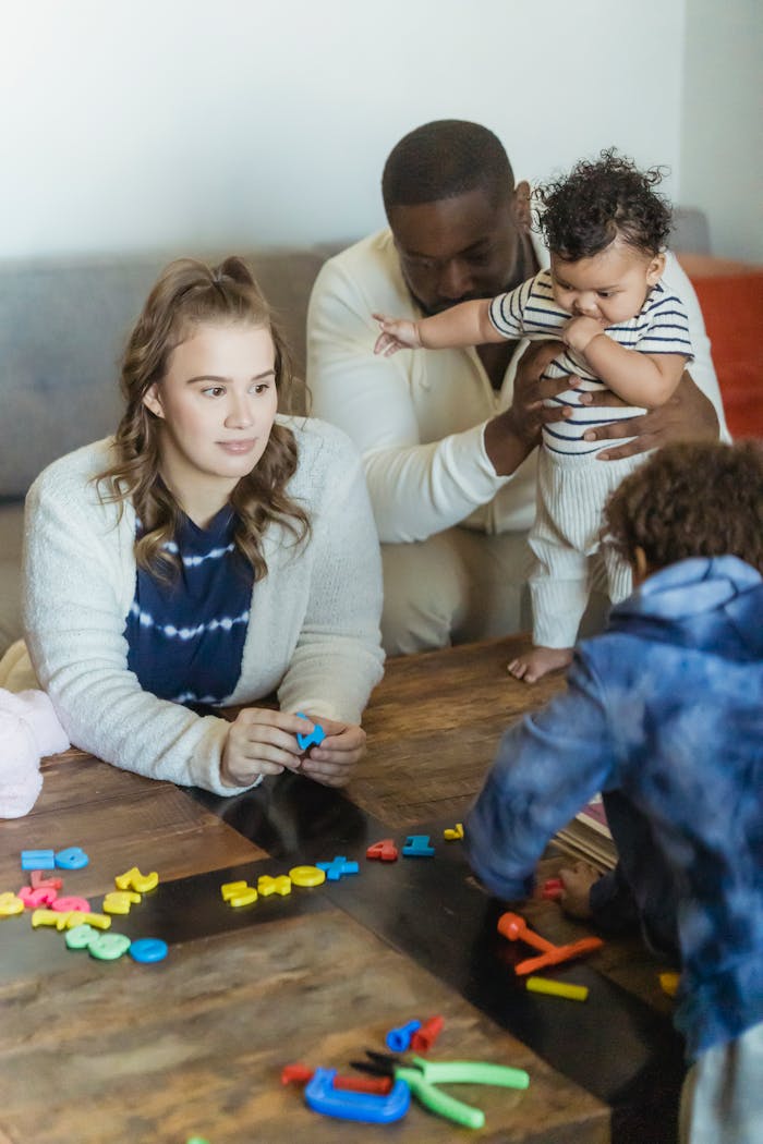 Crop anonymous boy playing with toy numbers against multiethnic parents with toddler kid at home